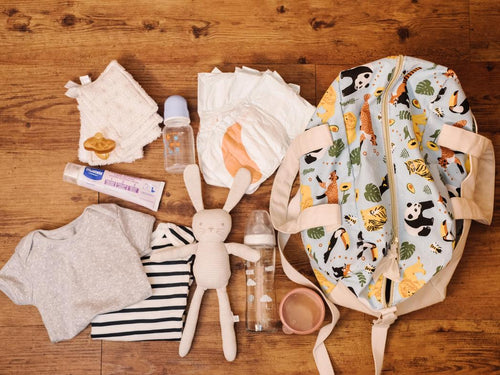 Una familia prepara la maleta de viaje de su bebé colocando todo lo necesario encima de la mesa - Mustela España - 1