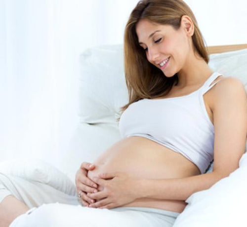 Mujer sentada en un sillon blanco tocándose la tripa - Mustela España - 1