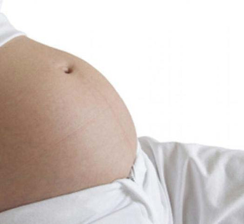 Primer plano del vientre de una mujer embarazada que usa productos Mustela para el cuidado de su piel - Mustela España - 1