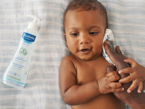 Un padre está limpiado la cara de su niño con una ecotoallita discos de algodón BIO - Mustela España - 4