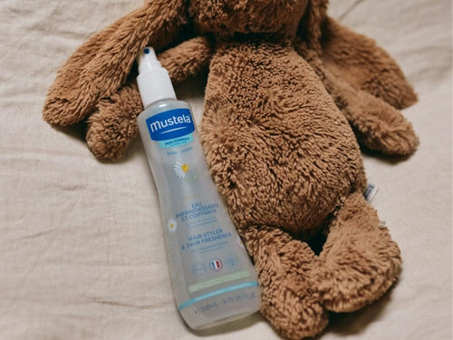 Bote de agua de peinado infantil de Mustela al lado de un peluche - Mustela España - 8