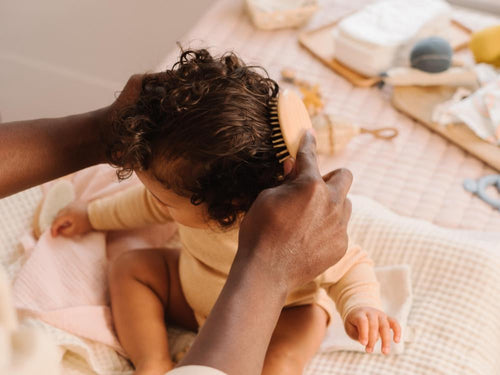 Un padre está peinando el cabello rizado de su niña después de aplicar el agua para peinar de Mustela - Mustela España - 6
