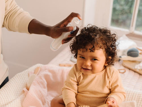 Una padre usa el Agua para peinar de Mustela en el pelo de su niña con pelo rizado. slider - Mustela España - 5