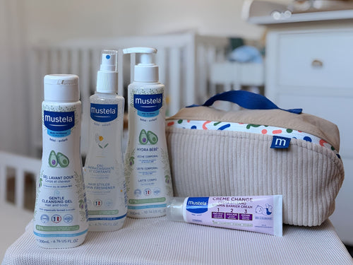 Neceser Vanity de Mustela con detalles verdes. A su lado os 4 productos que contiene: gel de baño suave, agua para peinar refrescante, leche corporal y crema de pañal. - Mustela España - 3