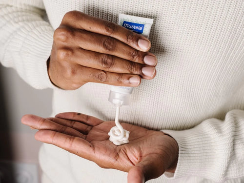 Padre se aplica un poco de crema facial para piel seca de Mustela en las manos para hidratar y nutrir la cara de su bebé. - Mustela España - 5