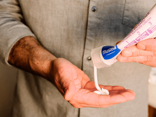 Padre se aplica un poco de crema bálsamo 123 en la mano para prevenir y aliviar la pañalitis del bebé. - Mustela España - 5
