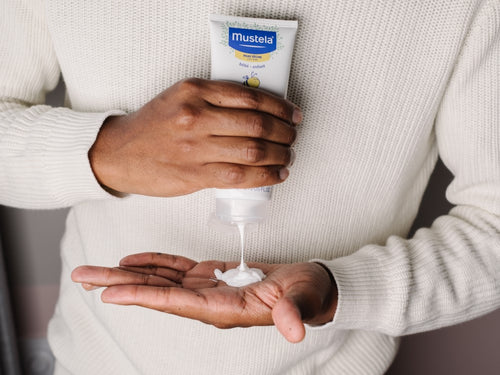 Padre aplica un poco de leche hidratante corporal para piel seca de Mustela en la palma de su mano. - Mustela España - 5