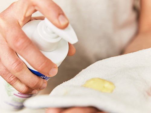 Madre aplica un poco de linimento Mustela en una toalla para limpiar con suavidad el culito de su bebé al cambiarle el pañal. - Mustela España - 5